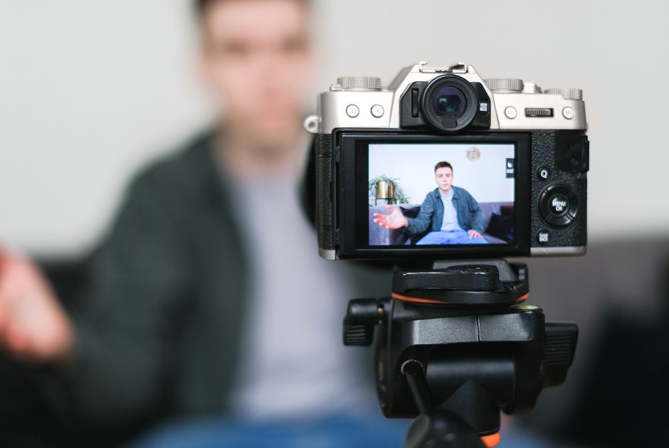 A vlogger filming themselves with a compact camera