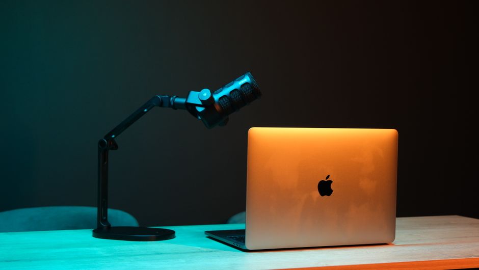 Home studio desk with podcast microphone and warm lighting against a dark backdrop